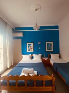 a blue bedroom with two beds and a blue wall at Garden Guesthouse in Skala Kallirachis