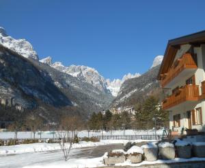a building with snow covered mountains in the background at Garnì Lago Alpino in Molveno +23 photos