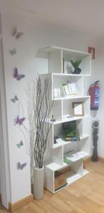 a white book shelf with butterflies on the wall at Caminante in Belorado