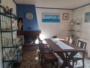 ein Esszimmer mit einem Tisch und einer Uhr an der Wand in der Unterkunft Chez Kat Location Ile de Groix in Groix