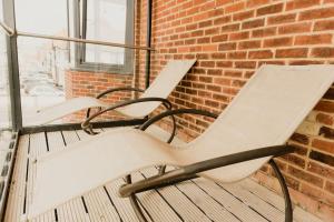 three white chairs sitting on a porch next to a brick wall at The Sea Deck Apartment - Westbrook Bay Beach - By Goldex Coastal Breaks in Kent