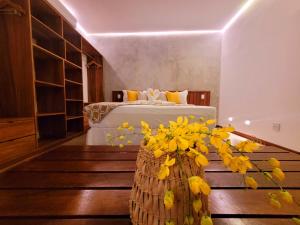 um quarto com uma cama e um vaso de flores amarelas em Villa Valencia em Jericoacoara