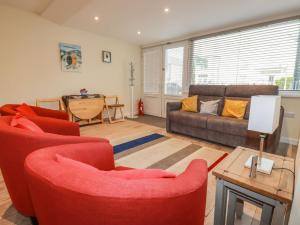 een woonkamer met 2 rode stoelen en een bank bij Falcon House in Tintagel