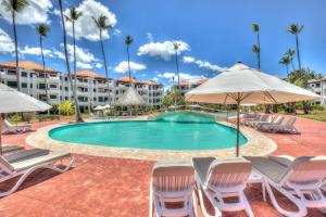- une piscine avec des chaises et des parasols dans un complexe dans l'établissement Ultra Cosy 2 Bedroom Beach Apartment - K-302, à Punta Cana
