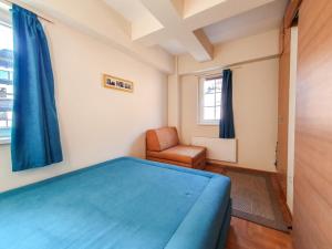 a bedroom with a blue bed and a chair at Apartman Cvejic - Suncani apartmani in Brzeće