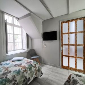 um quarto com uma cama, uma televisão e janelas em Casa Hostal Paso por La Serena em La Serena