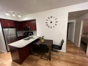 a kitchen with a table and a clock on the wall at Prestigious 2-Bdrm Condo - across from Scotiabank Arena in Toronto