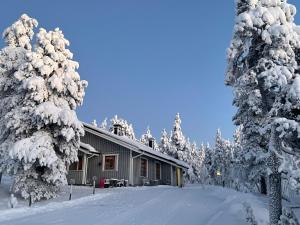 une maison recouverte de neige devant les arbres dans l'établissement Panoraama 1, à Saariselka