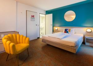 Habitación de hotel con cama y silla amarilla en Hessenland Hotel Kassel Innenstadt by Stay Awesome, en Kassel