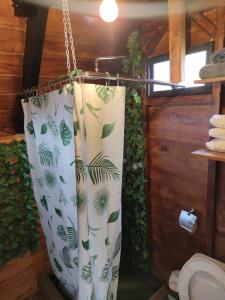 a bathroom with a shower curtain with green plants at Alpina Glamping en Latacunga in Saquisilí