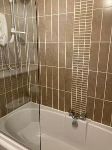 a bathroom with a tub with a glass shower door at Beautiful 2 bedroom flat overlooking golf course in Carnoustie
