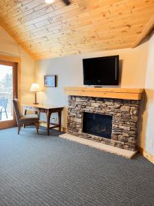 a living room with a stone fireplace with a flat screen tv at Ruttger's Bay Lake Resort in Deerwood