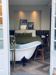 B&B Sur Place في هاوسن: غرفة نوم مع سرير وحوض استحمام بجانب سرير