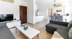 una sala de estar con un sofá y una mesa en Modern Apartment U2 - Zias with lovely views in heart of Aphrodite Hills, en Kouklia