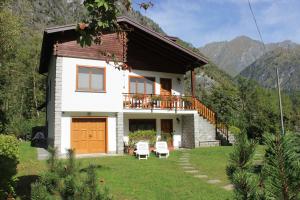 ein kleines weißes Haus mit einem Balkon und 2 Stühlen in der Unterkunft Villa Egle in Antronapiana