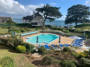 a large swimming pool with chairs and the ocean at Ty Corn in Bénodet