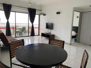 uma sala de estar com uma mesa preta e cadeiras em Happy Home 26 Sri Sayang Batu Ferringhi em Batu Ferringhi