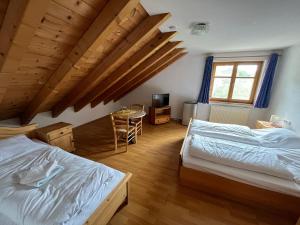 1 Schlafzimmer mit 2 Betten, einem Tisch und einem Fenster in der Unterkunft Landgasthof Jägerhaus in Immenstadt im Allgäu