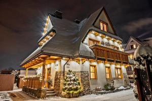 a house with a christmas tree in front of it at Willa Mały Dworek in Zakopane
