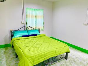 um quarto com uma cama com um cobertor amarelo em TR Bungalow em Ban Tha Rua