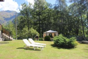 two white chairs in a yard with a gazebo at Villa Egle in Antronapiana