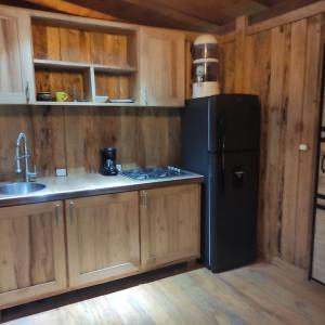 cocina con nevera negra y armarios de madera en Zen Oasis del Bosque, ¡A place to reconnect!, en Calima