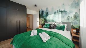 a bedroom with a large green bed with towels on it at Apartamenty Sun & Snow Resorts C Białka Tatrzańska z sauną in Białka Tatrzanska