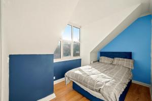 a blue bedroom with a bed with a blue wall at 2 Bed Central Hub in Medway in Chatham