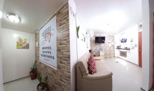een woonkamer met een bank en een bakstenen muur bij Hotel Santa Teresita in Yopal