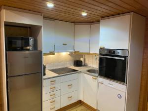a kitchen with white cabinets and a stainless steel refrigerator at Panoraama 2 in Saariselka