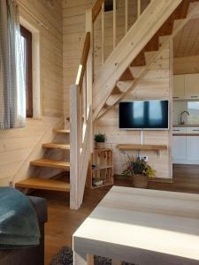 a living room with wooden stairs and a flat screen tv at Leśna Przystań - Domki całoroczne in Grywałd