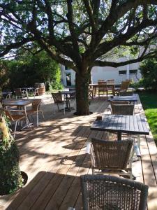 una terraza de madera con mesas y sillas bajo un árbol en Hôtel Bon Repos, en Barbezieux