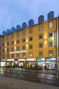 un gran edificio amarillo con gente caminando delante de él en BATU Apart Hotel, en Múnich