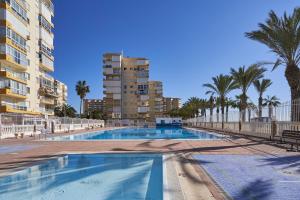 een groot zwembad met palmbomen en gebouwen bij Apartamento Amador in Algarrobo-Costa