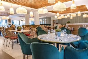 Grand Prix Hôtel & Restaurant في لو كاستليت: مطعم به طاولات وكراسي وثريات