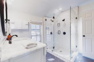 a white bathroom with a shower and a sink at The Pink House on Main - Upper in Eureka Springs