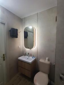 y baño con aseo, lavabo y espejo. en Apartament Tzar Kaloyan, en Burgas