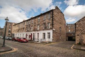 an old brick building with cars parked in front of it at RÌGH Properties - Luxury West End Artisan Apartment in Edinburgh