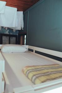 - un grand lit blanc avec une couverture rayée dans l'établissement Eau Berges - Chez Mamie, à Vicdessos