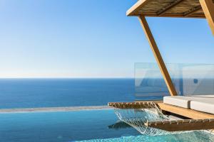 a resort infinity pool with a hammock and the ocean at Mani Theasis in Stoupa