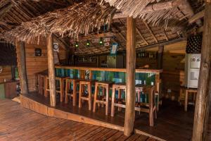 bar z drewnianymi stołami i krzesłami w kabinie w obiekcie Miseni Retreat w mieście Saadani