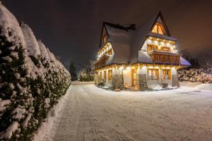 a house covered in snow at night with lights at Willa Mały Dworek in Zakopane