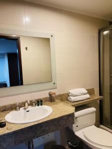 a bathroom with a sink and a toilet and a mirror at Hotel La Sabana in Bogotá