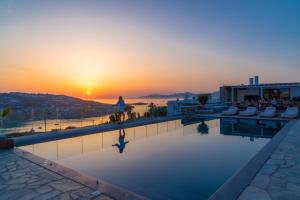 a swimming pool with a sunset in the background at Sonia in Mikonos