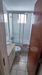 y baño con lavabo, aseo y espejo. en Departamento Avenida Del Mar, en La Serena