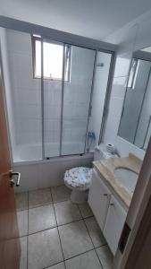 y baño con lavabo, aseo y espejo. en Departamento Avenida Del Mar, en La Serena