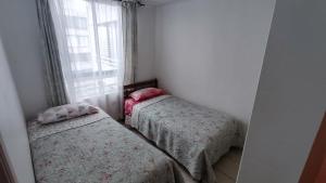 2 camas en una habitación pequeña con ventana en Departamento Avenida Del Mar, en La Serena