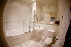 a bathroom with a tub and a toilet and a sink at Chelmsford Serviced Apartments in Chelmsford +3 photos