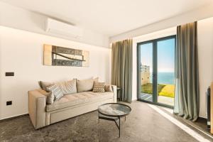 a living room with a couch and a view of the ocean at Mani Theasis in Stoupa +37 photos