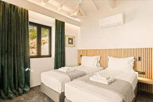 two beds in a room with green curtains at Mani Theasis in Stoupa